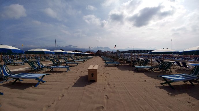 Forte dei Marmi: ombrelloni e lettini blu, spiaggia ordinata e Alpi Apuane sullo sfondo