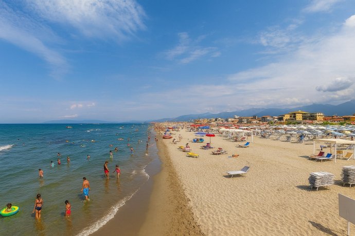 Lido di Camaiore: bagnanti in acqua, mare calmo e stabilimenti sulla sabbia