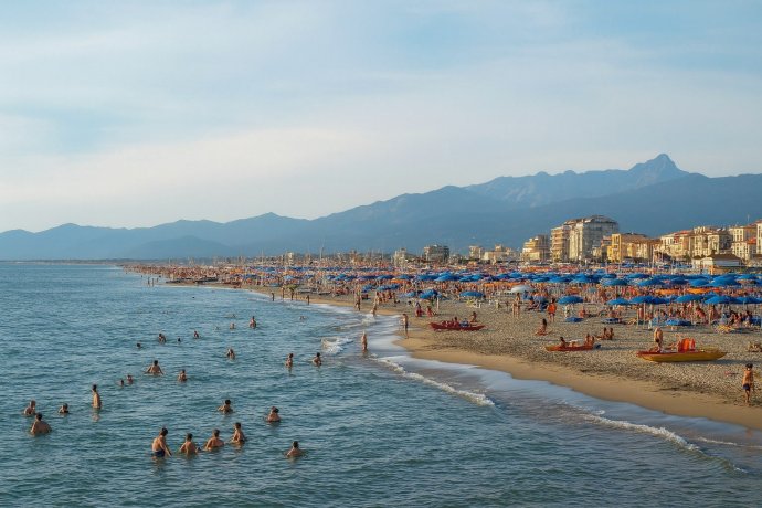 Spiaggia di Viareggio: ombrelloni e bagnanti, mare calmo e Alpi Apuane sullo sfondo, Versilia.
