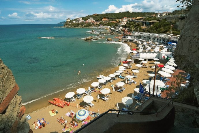 Baia del Quercetano a Castiglioncello con ombrelloni bianchi e mare turchese