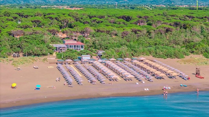 Vista aerea della spiaggia Dune a Marina di Castagneto con ombrelloni, pineta e mare calmo.