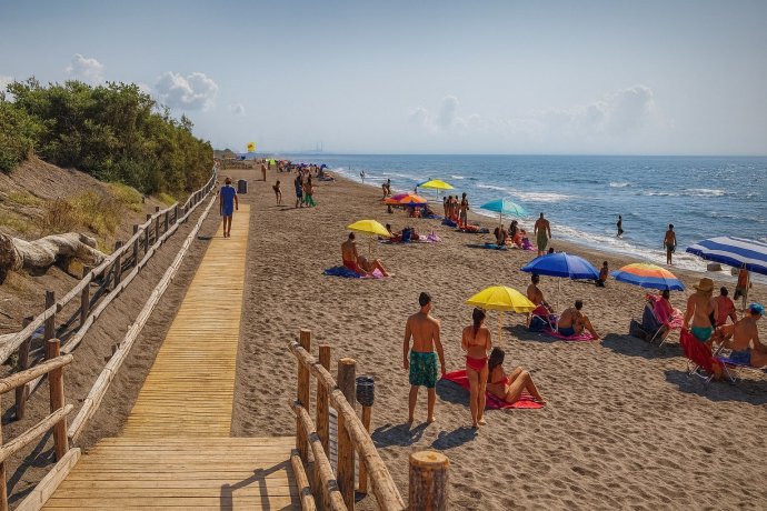 Passerella in legno sulla spiaggia di Macchiatonda, ombrelloni e bagnanti a Capalbio.