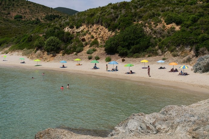 Caletta di Laconella (Isola d’Elba): sabbia chiara, acqua turchese, scogliera e ombrelloni.