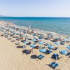 Spiaggia con ombrelloni blu e bianchi, mare all'orizzonte.