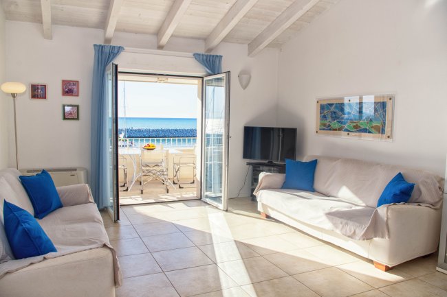 Salotto luminoso con divani e balcone vista mare.