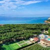 Vista aerea di un resort con piscine e campi sportivi vicino al mare.