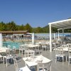Ristorante all'aperto con vista sulla piscina affollata e montagne sullo sfondo.