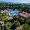Complesso con piscine, palme e strutture con tetti rossi vicino alla costa.
