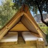 Tenda in legno con due letti singoli all'aperto, scenario naturale di sfondo.