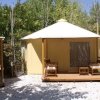 Una tenda glamping con veranda, mobili da esterno e tetto bianco.