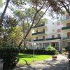 Edificio bianco, giardino con alberi e vialetto con prato.