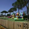 Un'area giochi all'aperto con gonfiabili colorati, alberi e una recinzione in legno.